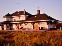 <b> Beautiful downtown Oba, ON </b> <br>
Another view of the CN Oba, ON station from early July 1976. <br>
The platform and surrounding grounds are littered with common place items (at the time) seen at stations throughout the north. 45-gallon drums of gasoline, propane tanks and oil (kerosene) drums for the station agent and work crews in the yard. A freshly painted baggage cart rests in front of the station waiting on its next load of arriving or departing cargo. <br>
Lots of antennas on the roof for tv and radio communications.