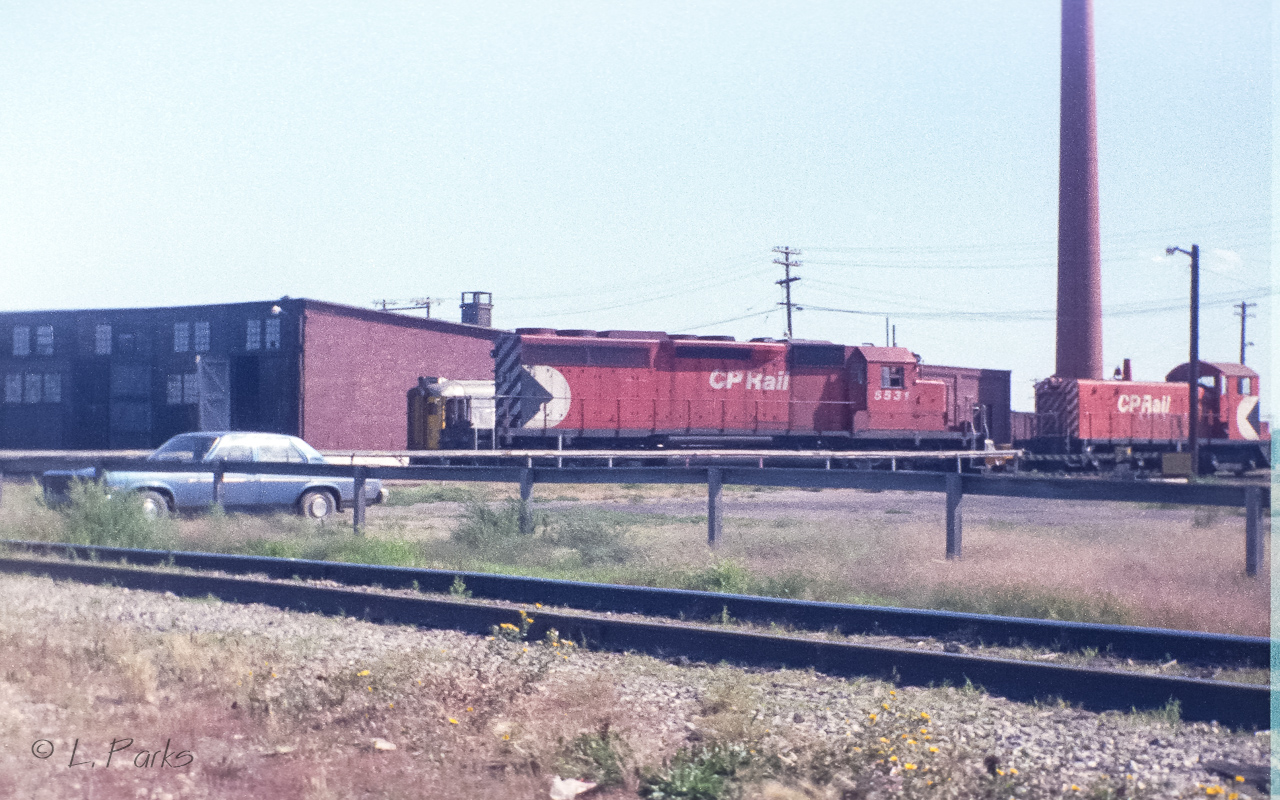 Things have changed since this picture. Big red smoke stack is gone, the little SW's are gone, more of the round house has been removed. Just the part with doors open remains. No more rail liners. The 5531 is retired and sold (2000??) to another road. By how much of the main yard has been removed, it cannot be much longer until CP vacates the property. The Whyte avenue area has been waiting a long time for this to happen. Photo taken with a little 110 pocket camera.