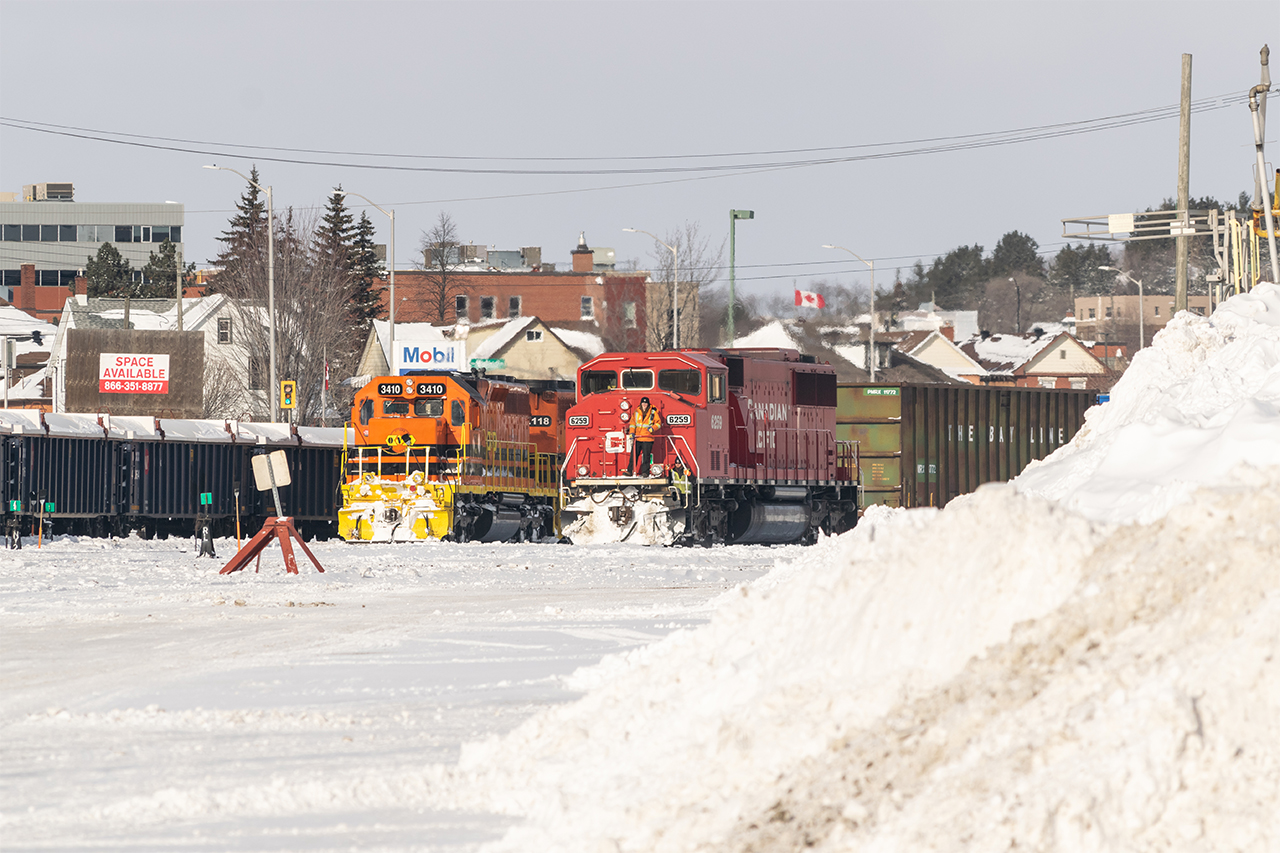 After a couple of days of snowfall, Huron Central power (OVR units 3410 and 2118) are soaking up the afternoon sun. Meanwhile, a rare-ish CP SD60M appears beside one of Sudbury's many large snowbanks. Behind it all, a Canadian flag flaps in the winter breeze, two days after its 60th birthday.