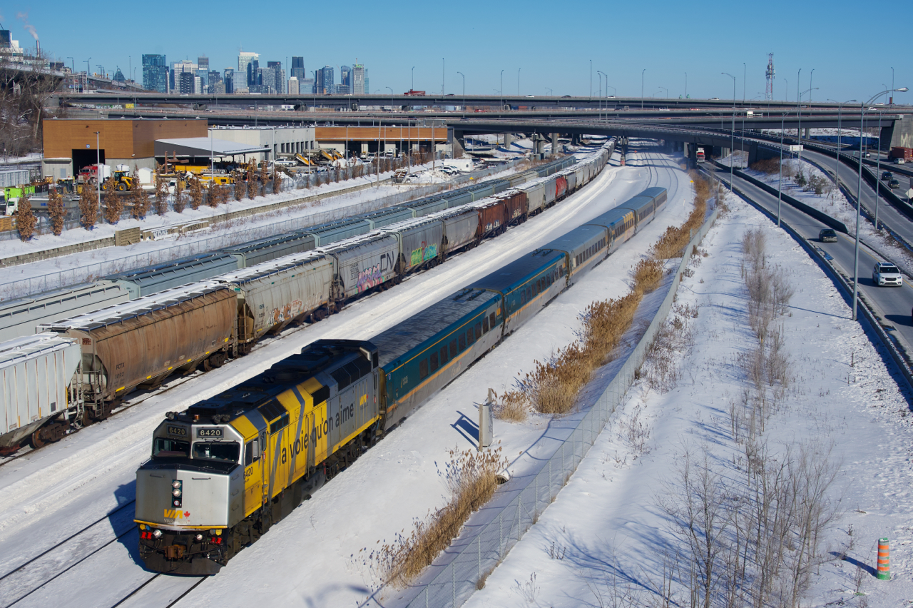 VIA 67 is passing grain cars with wrapped VIA 6420 leading. The grain cars closest to VIA 67 are about to be lifted by CN X400.