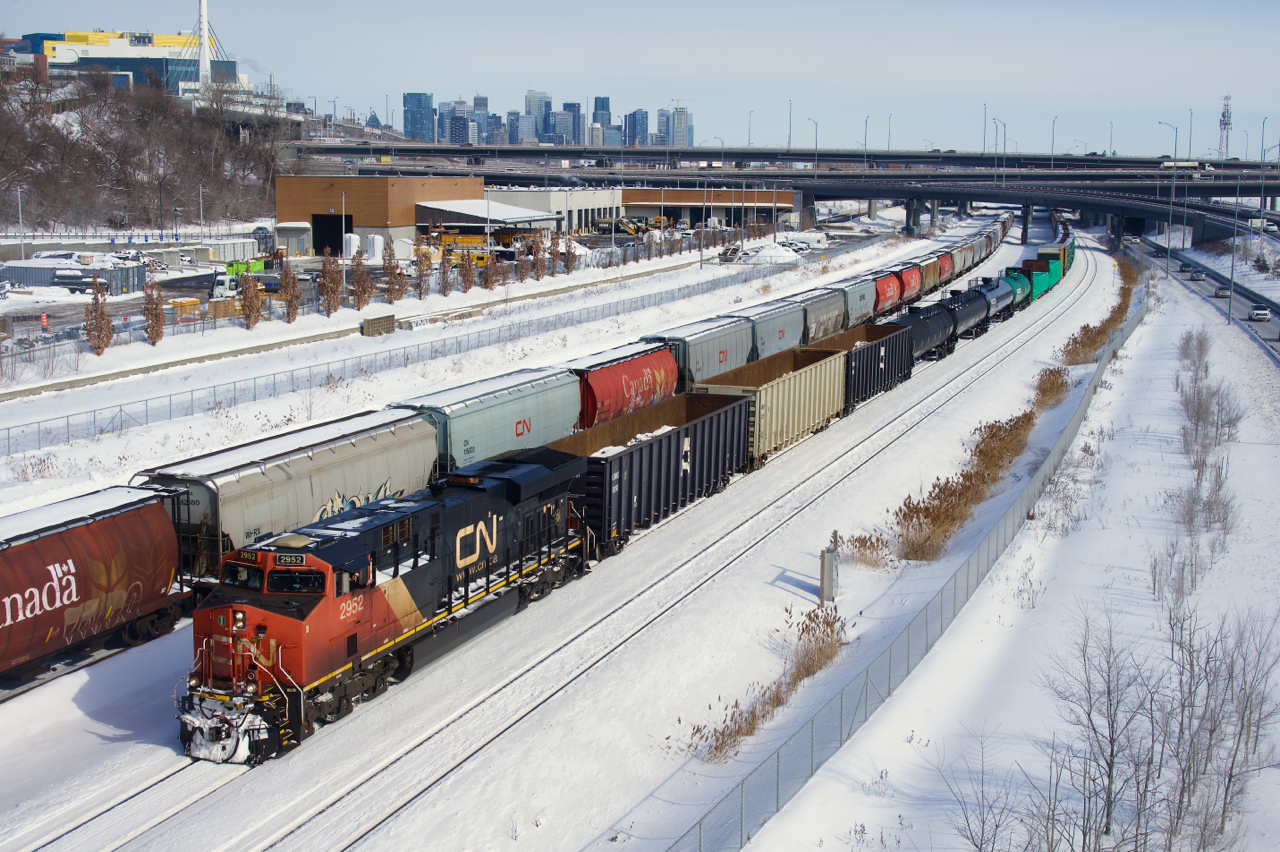 The conductor waves as CN 305 passes parked grain cars.