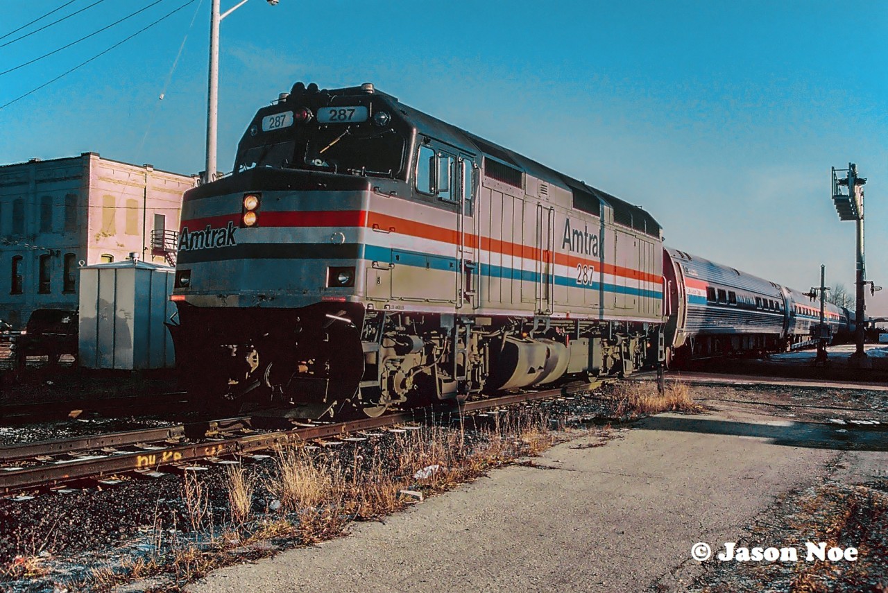 The westbound “International” to Chicago, Illinois from Toronto, Ontario is making its station stop at Weber Street in Kitchener, Ontario on the CN Guelph Subdivision. Train #85 is powered by Amtrak F40PH 287, which will soon continue on to Stratford. At this time, 85 was scheduled in the morning at Kitchener at 09:34, not long after #84, which was due at 09:06, requiring both trains to have a morning meet not far out of the city.