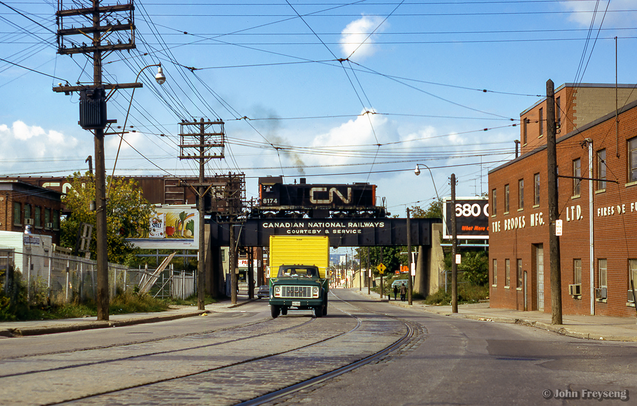 Working local industries along the Newmarket Sub, CN 8174 rumbles north over Rogers Road.  This scene has changed quite a bit, with the CNR bridge lettering now replaced with Metrolinx insignia, and most industries removed.  The site at left is now home to a school, while housing has sprung up on the former Brooks Mfg Ltd site at right.  Gone too is the Rogers Road streetcar line, which last ran just two years after this photo in July 1974.  Further information found HERE.

Scan and editing by Jacob Patterson