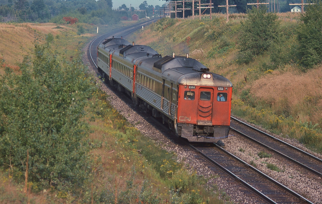 At track speed: VIA CN #655,  daily except Saturday, with RDC-3 / RDC-9 / RDC-1 combo,


The view from the Bee Bridge, CN Newtonville crossovers in the background. September 3, 1978 Kodachrome by S.Danko


  interesting: 


 #655 (late afternoon) and #652 (noon hour)  were un-named fast Budd Car runs, Kingston – Union 158 miles in 2:45, with five intermediate stops,   The' Ontarian' Budd Car trains #651 (early am) & # 656 (evening).


and for the Siemens Venture fans: note the Budd Cars 12 light weight axles, at track speed: 90 mph, on jointed rail.


RDC-3 weight 231,000 pounds, with 51% weight on two driving axles; Siemens Venture car weight 112,000 pounds each plus Siemens Charger loco weight: 260,000 pounds.


Three RDC 's weight approximately 686,000 pounds on 12 axles ; VIA Venture five car  train weight approx 820,000 pounds on  24 axles.


More:


       VIA #652  


sdfourty