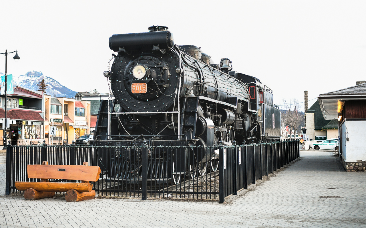 Fire breathing monster  
CN 6015 is looking good as always sitting on its perch at the Jasper, AB station on this cold, windy, and overcast March morning. 
Behind me and the store fronts at left there is terrible forest fire damage from last summer, but CN 6015 and the surrounding railway buildings managed to come through the devastation completely unscathed.