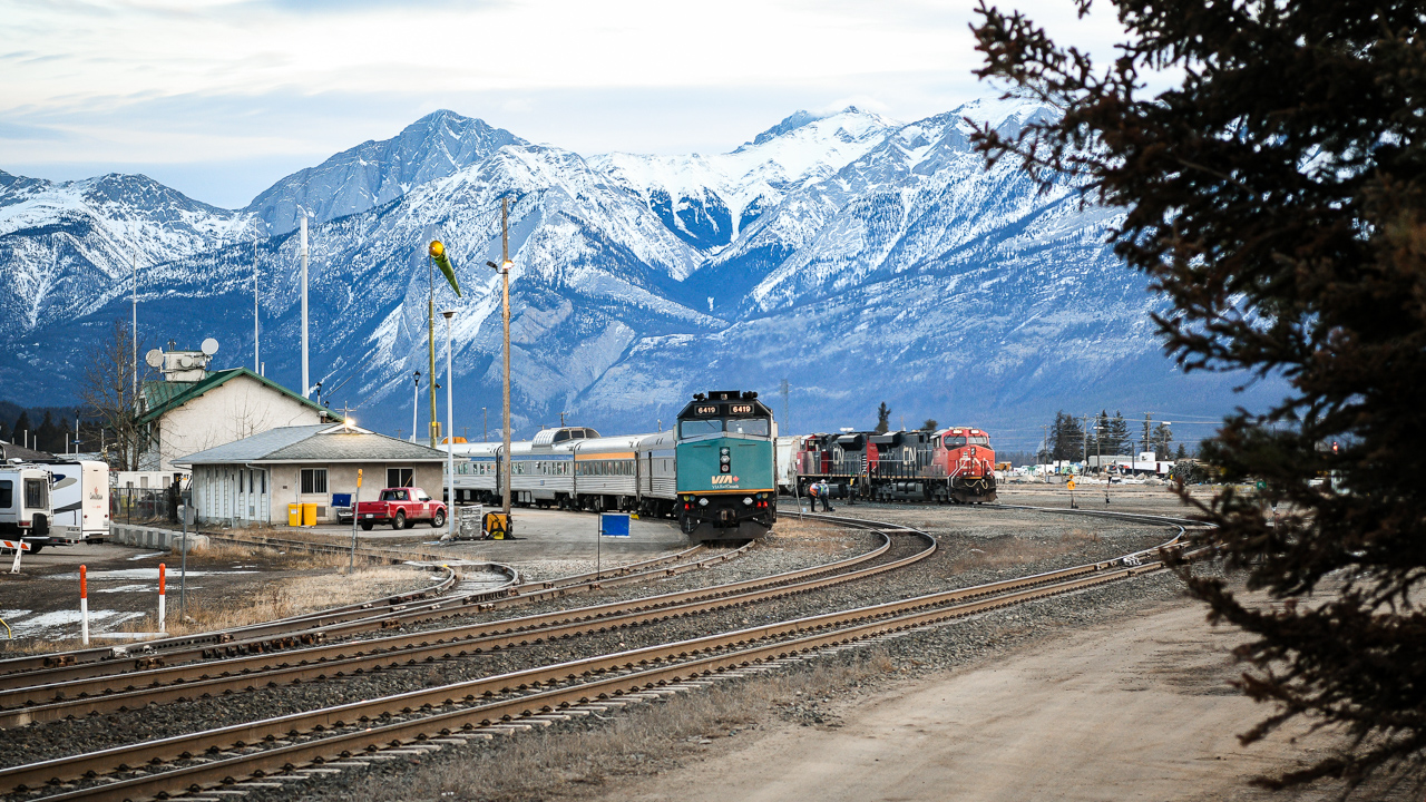 Crisp and cold morning  
While VIA 001 The Canadian is getting a full service and head end crew change at Jasper, AB I had plenty of time to walk around town for some pics. 
Standing at the west end entrance to CN's yard and Operation Centre at Hazel Avenue I snapped VIA 001 and a CN westbound grain train waiting to depart. 
It was a frosty cold and windy morning but well worth the walkabout. 
There was plenty of construction activity visible as the town is well underway to rebuilding.