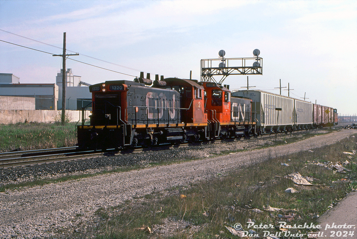 A short CN local powered by SW1200RS units 1320 and 1335 works in the industrial area of Brampton at Kennedy Road, seen here at the west end of the "Peel" interlocking where the double track main became single track, between here and Brampton East (Queen Street) to the west. This arrangement lasted into the late 2000's when the Halton Sub was finally doubletracked through downtown Brampton (eliminating Brampton East, and moving Peel interlocking west to Centre Street).

There were dozens of customers in this area of Brampton west of Highway 410 receiving rail service at the time, including IKO Industries, General Latex, American Motors (AMC) Brampton Assembly, CIL (later Graphic Packaging), Canada Colours & Chemicals, and Argo Plastics.

Peter Raschke photo, Dan Dell'Unto collection slide.