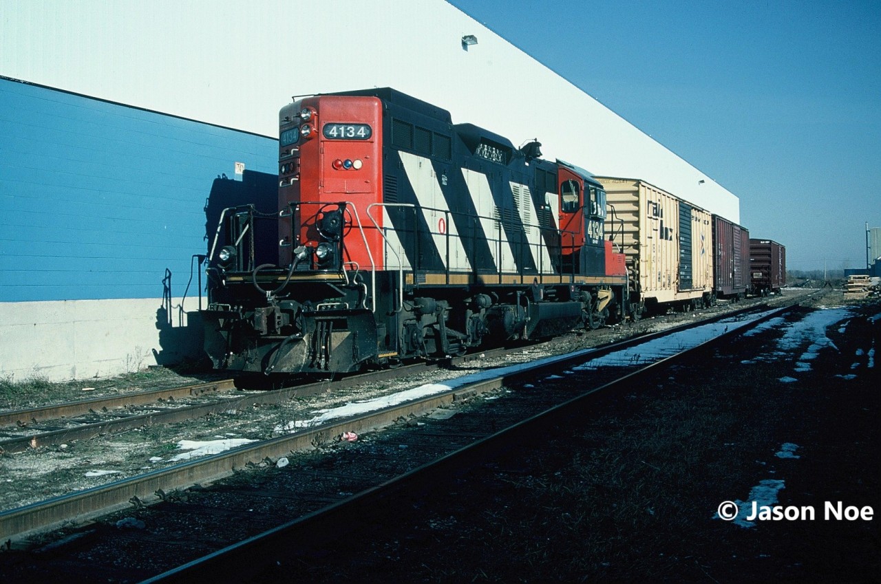 At one time, the CN Galt Industrial Spur in Cambridge was a thriving section of track that saw daily service during the week by a local job based out of Kitchener. Branching-off the Fergus Spur near Highway 401, the spur was the regular destination for CN 580 during the 1990’s. Two customers, McPherson and Inglis were situated at the end of the spur where it crossed Franklin Boulevard and provided the bulk of the traffic for the CN local. However, in November 1994, Inglis had announced that appliance production at the factory would be phased out by the second quarter of 1995. 

Here in December 1994, CN 580 with GP9RM 4134 patiently waits as Inglis workers completed loading boxcars with new locally manufactured appliances for Canadian markets. At some point in 1995, the facility loaded its last boxcars and closed, leaving one less customer on the spur. Interestingly, both tracks still remain in place today, although disconnected, and the large building is used for office space as well as by children’s clothier Carter's Oshkosh.