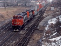 CN GP40-2L(W) 9411 and SD40-2W 5357 lead an intermodal train on the CN Grimsby Sub through the industrial area of Hamilton, passing Ferguson Avenue where the Hagersville Sub (on the right, by then just a short spur) and N&NW Spur (on the left) branch off the mainline.<br><br><i>Reg Button photo, Dan Dell'Unto collection slide.</i>