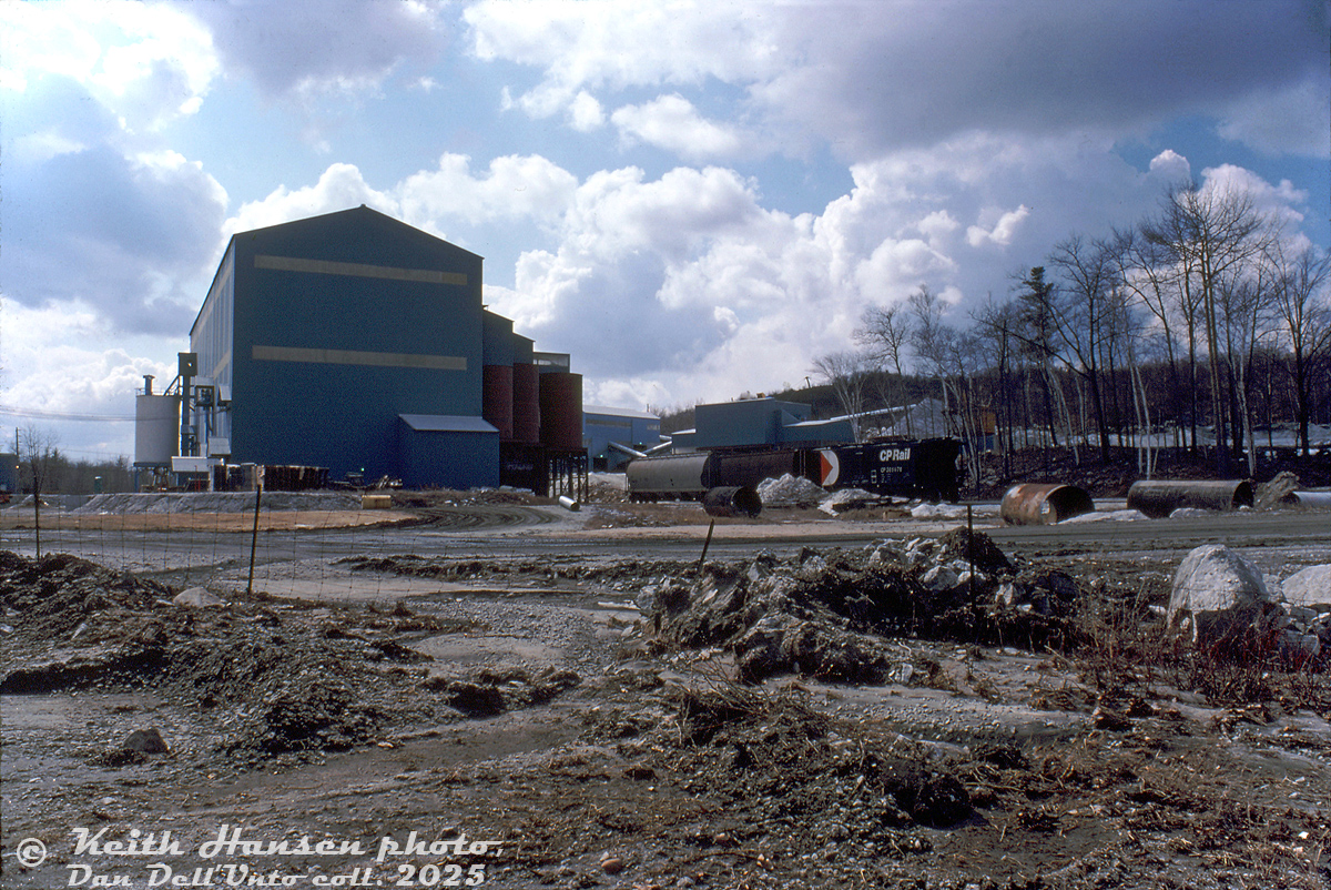 The Unimin Blue Mountain mine is shown at Blue Mountain (Havelock-Belmont-Methuen Township), at the end of CP's Nephton Sub, looking east off County 6 Road. Three CP hoppers visible by the mine: an old CP "slab side", a 383000-series aluminum "tank hopper", and a more modern cylindrical hopper.

The Blue Mountain and Nephton nepheline mines were the reason the CP constructed their Nephton Sub from Havelock all the way to the north in the 1950's, and keep operating it plus the Havelock Sub to this day (for more information, see the late Ray Kennedy's page on Old Time Trains).

Keith Hansen photo, Dan Dell'Unto collection slide.