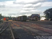 A look from inside Canadian Pacific's Orangeville Yard on a slightly overcast day in September 1973 shows a bit of equipment lingering around. This view is looking north to Town Line, showing a pair of CP SW1200RS "BLU" (Branch Line Units) parked near the old bunkhouse, with part of the station visible further back. A few cars sit in the yard, with the red ends of a flanger car visible on its own. The switch to the Clorox plant siding is visible in the foreground.<br><br>At the time there were still numerous branchlines radiating from the Orangeville area to the north and west. Over time as those branchlines were abandoned, Orangeville's importance as a junction point diminished. It had about a two-decade reprieve when the Orangeville Brampton Railway acquired the line from CP in 2000, but finally succumbed to economic and political pressure at the end of 2021 when service on the whole remaining line from Streetsville to Orangeville was ended.<br><br><i>Keith Hansen photo, Dan Dell'Unto collection slide.</i>