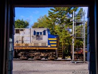 The mid train DPU on CN Q124 squeals past the VIA station shelter at Washago as the train negotiates the twists and turns through town.