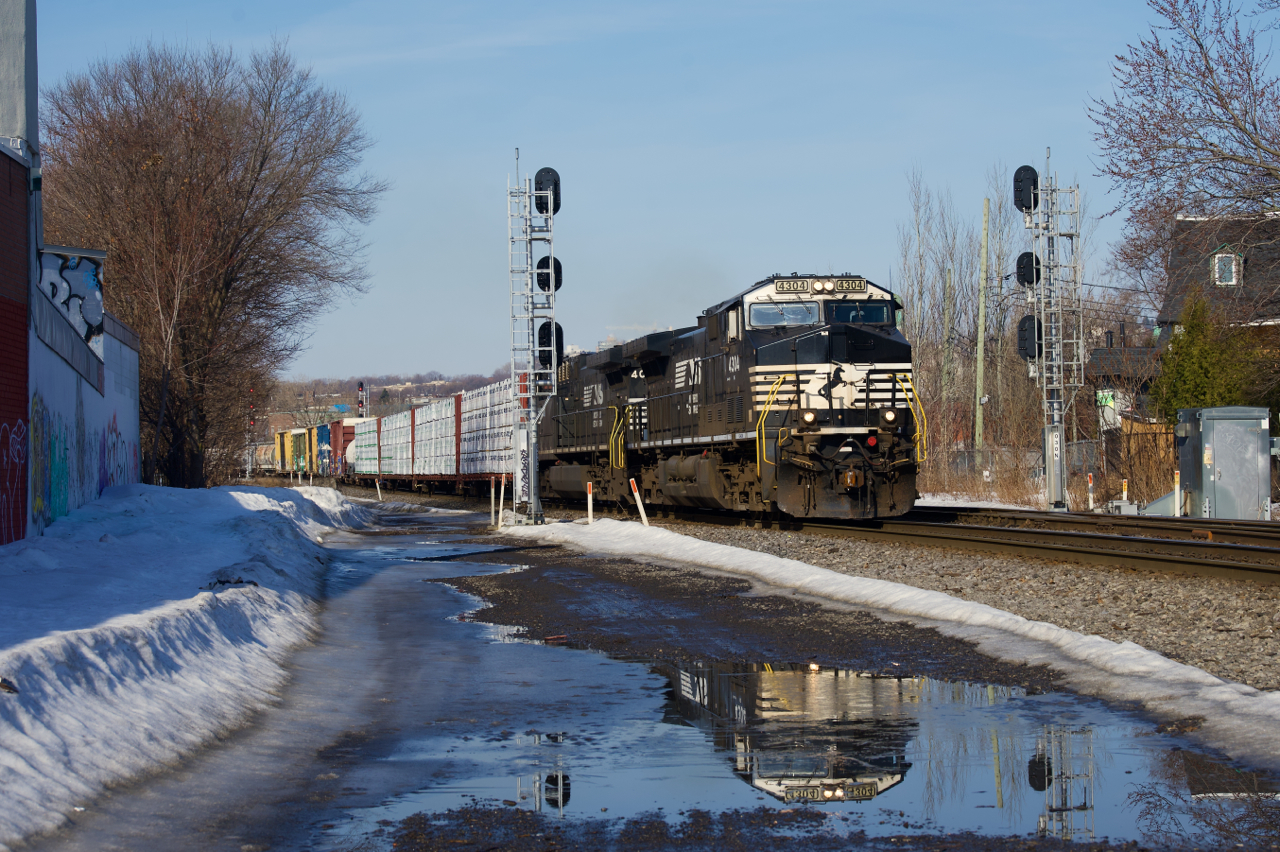 Normally running in the middle of the night, a late CN 528 is reflected in some melted ice as it approaches MP 3 of the Montreal Sub. The train has NS 4340 & NS 4016 for power and 47 cars.