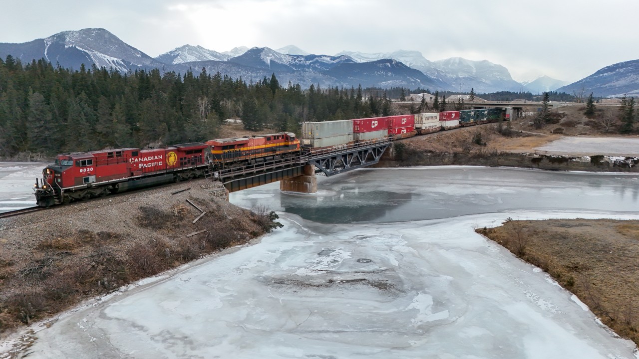 CPKC 112-23 leaves the Rocky Mountains behind as they enter the foothills of Alberta.  After some power moves in Calgary, the train will be traversing the Canadian Prairies. CPKC 112-23: CP 9830, KCSM 4756, CN 3274, CN 3122 - DP 2x1x1