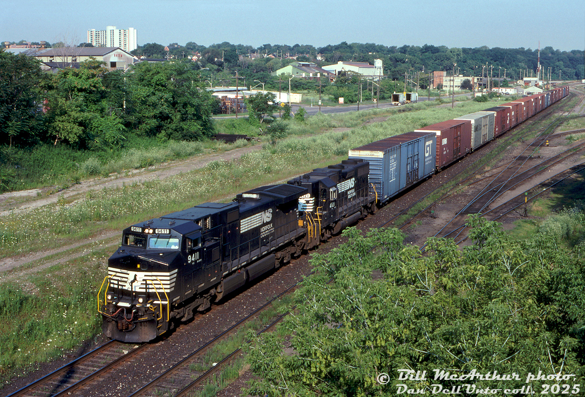 NS C44-9W 9411 and GP38AC 4121 roll #328 (autoparts train from St. Thomas to Buffalo) through CN's Stuart St. Yard on a sunny morning. The CN freight shed and diesel shop are visible in the background, both had seen better days. The old Rheem warehouse is also visible amid the overgrown foliage and industrial scenery.

While a new GO station and CN transloading facility have set up shop here in more recent years, all the empty lots and demolished factories make it seem like a bit of a deindustrialized wasteland.

Bill McArthur photo, Dan Dell'Unto collection slide.