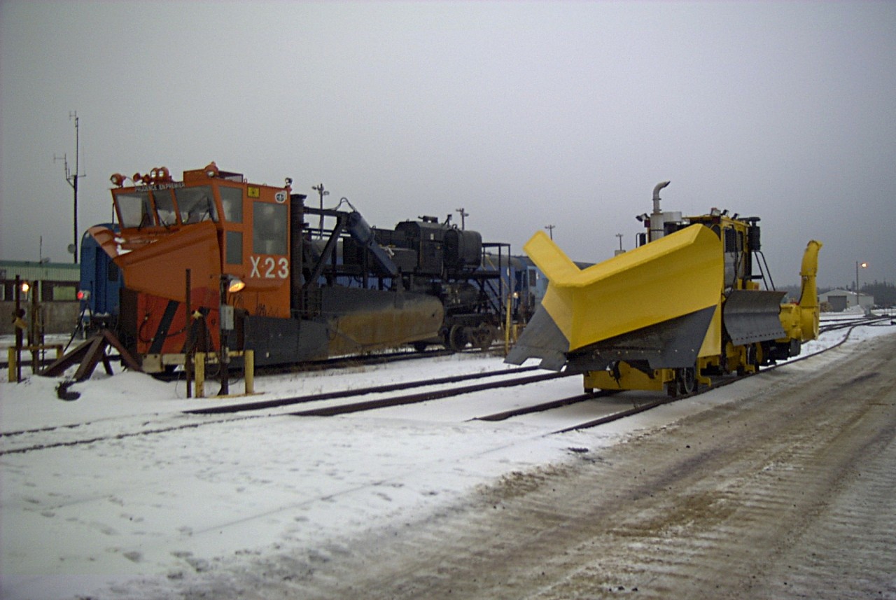 Keeping the ore moving  
It's early in the morning and we're getting the equipment ready to head out for a day of plowing and sweeping in the yard at Port Cartier, QC. 
43-year-old (at the time) QCM X-23 is a Jordan Type A spreader serial No. 899, built in 1960. It is equipped with a medium front blade with custom upper snow curls, straight side wings, custom cab, raised rear platform, and diesel-powered hydraulic control cylinders. 
Brand new (at the time) QCM P-722 is a Nordco M2-14 ballast regulator/snow fighter, serial No. 800208, built in 2003. 
I always enjoyed working with the folks at the Cartier Railway. 
At the QCM main shop complex in Port Cartier QC November 13, 2003.