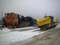 <b> Keeping the ore moving </b> <br>
It's early in the morning and we're getting the equipment ready to head out for a day of plowing and sweeping in the yard at Port Cartier, QC. <br>
43-year-old (at the time) QCM X-23 is a Jordan Type A spreader serial No. 899, built in 1960. It is equipped with a medium front blade with custom upper snow curls, straight side wings, custom cab, raised rear platform, and diesel-powered hydraulic control cylinders. <br>
Brand new (at the time) QCM P-722 is a Nordco M2-14 ballast regulator/snow fighter, serial No. 800208, built in 2003. <br>
I always enjoyed working with the folks at the Cartier Railway. <br>
At the QCM main shop complex in Port Cartier QC November 13, 2003.
