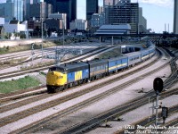 The sun briefly came out just in time for Bill McArthur to catch VIA Rail train #9, The Canadian (Toronto-Sudbury run, reinstated back in June) departing downtown Toronto Union Station at Bathurst Street. Rebuilt VIA FP9ARM 6313 leads F9B 6618 and a mix of ex-CN and ex-CP equipment (curiously with no Skyline dome) heading up the CN Weston Sub for the Newmarket Sub.<br><br>October 6th of 1985 would be a Sunday, and the sun angle suggests an afternoon departure. Bathurst North Yard is empty, while a weekend GO consist is seen near John Street interlocking tower in the distance. Some of the old CN/VIA Spadina Roundhouse servicing facilities can be seen to the right in shadow, not long for this world as they would be demolished for construction of the Skydome (Rogers Centre) in a year or two.<br><br>VIA 6313 was one of the CN Pointe St. Charles remanufactured "FP9ARM" units done in 1983-1984, rebuilt from VIA/CN 6526, and would be sold to Ohio Central upon retirement in the early 2000's. It would become most familiar to many here as <a href=http://www.railpictures.ca/?attachment_id=16156><b>Canadian Pacific 4107</b></a>, after CP purchased it and 6307 (CP 4106) from OHCR. At some point in the 70's it acquired those unique square-ish numberboard housings, probably after a collision or wreck, and it got its "Canadian Farr" vertical slat radiator grills off CP 1400 (and beaver crest) when CP rebuilt it as 4107.<br><br><i>Bill McArthur photo, Dan Dell'Unto collection slide.</i>