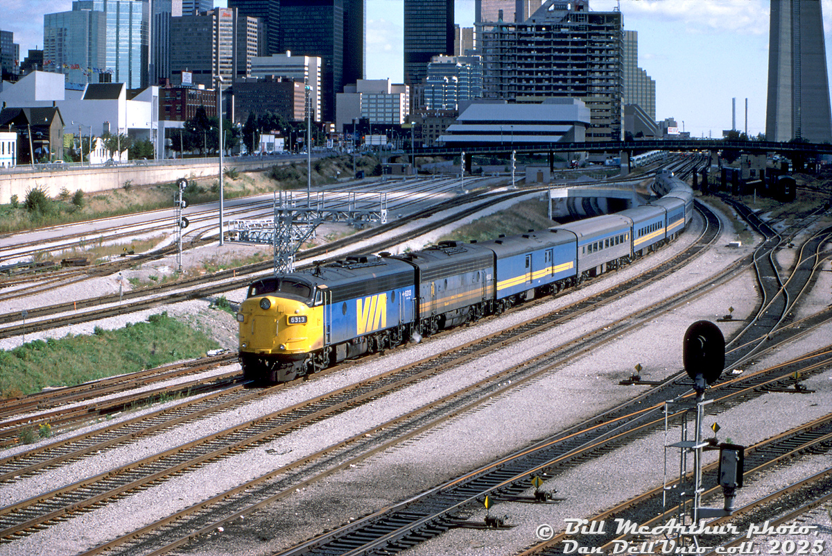 The sun briefly came out just in time for Bill McArthur to catch VIA Rail train #9, The Canadian (Toronto-Sudbury run, reinstated back in June) departing downtown Toronto Union Station at Bathurst Street. Rebuilt VIA FP9ARM 6313 leads F9B 6618 and a mix of ex-CN and ex-CP equipment (curiously with no Skyline dome) heading up the CN Weston Sub for the Newmarket Sub.

October 6th of 1985 would be a Sunday, and the sun angle suggests an afternoon departure. Bathurst North Yard is empty, while a weekend GO consist is seen near John Street interlocking tower in the distance. Some of the old CN/VIA Spadina Roundhouse servicing facilities can be seen to the right in shadow, not long for this world as they would be demolished for construction of the Skydome (Rogers Centre) in a year or two.

VIA 6313 was one of the CN Pointe St. Charles remanufactured "FP9ARM" units done in 1983-1984, rebuilt from VIA/CN 6526, and would be sold to Ohio Central upon retirement in the early 2000's. It would become most familiar to many here as Canadian Pacific 4107, after CP purchased it and 6307 (CP 4106) from OHCR. At some point in the 70's it acquired those unique square-ish numberboard housings, probably after a collision or wreck, and it got its "Canadian Farr" vertical slat radiator grills off CP 1400 (and beaver crest) when CP rebuilt it as 4107.

Bill McArthur photo, Dan Dell'Unto collection slide.