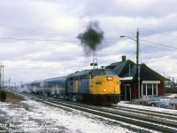 VIA FPA4 6782 coughs up a ball of black Alco smoke, presumably departing the VIA/CN Burlington West station after its stop on westbound train #73 from Toronto. Four blue and yellow coaches follow, being kept warm by steam heat emitted from 6782's onboard steam generator.<br><br><i>Bill McArthur photo, Dan Dell'Unto collection side.</i> 